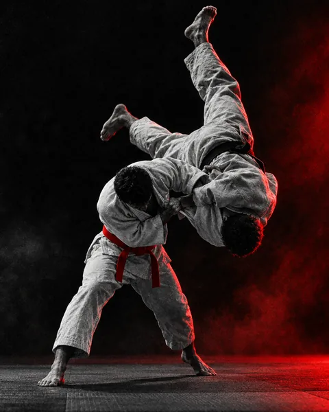 Judoka con judogi blanco proyectando a su rival con una técnica de judo sobre el tatami