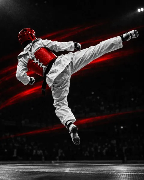 Taekwondista con dobok blanco lanzando una patada alta en un combate de taekwondo