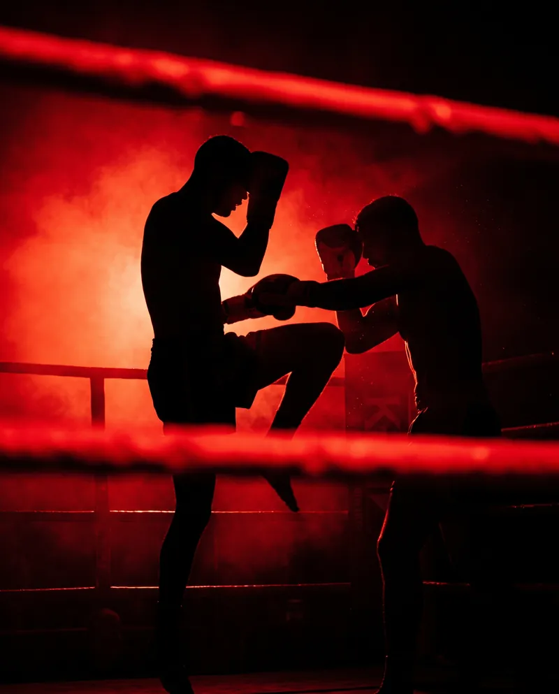 Dos luchadores de k-1 a contraluz en el ring, uno lanzando un rodillazo